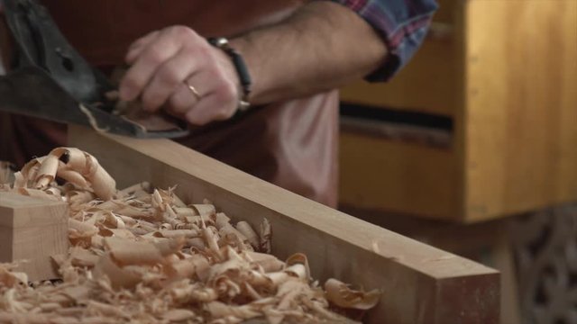 Cabinet Maker Planes Solid Wood in his Workshop/Cabinet maker planes the beech plank with a plane. He works in a small family joiner&rsquo;s shop. Slow motion