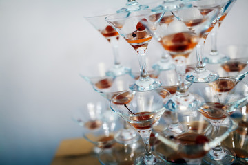Martini glasses make pyramid on glass table