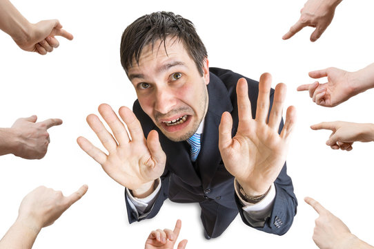 Many hands are pointing and blame stressed man. Isolated on white background.