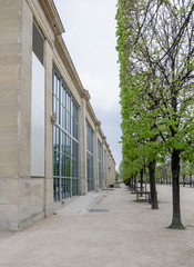 Perspective of a facade of the Musée de l'Orangerie (Orangerie museum) in Paris, France, and trees perfectly cut on a cloudy day