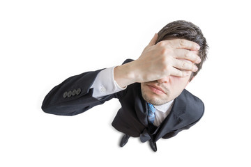 Young unhappy and stressed man made mistake and is covering his face with hand. Isolated on white...