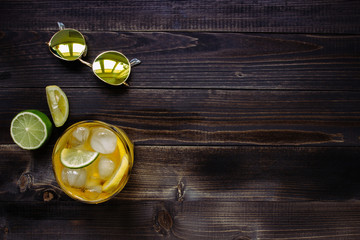 Ice drink. Ice tea, lemon, lime and sunglasses on the wooden table, top view. With copy space