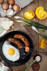 Breakfast served with scrambled eggs, fried sausages, yellow tomatoes and green onions in a rustic style.