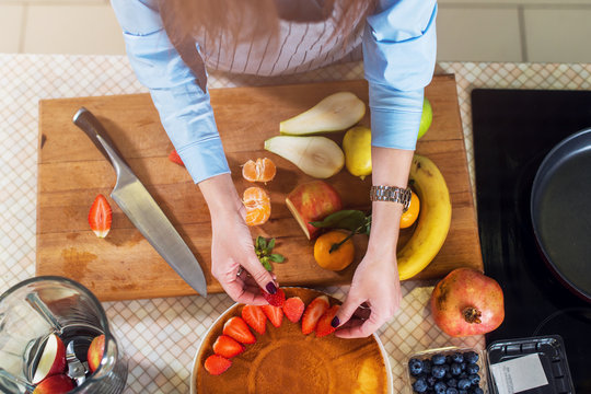 Top View Of Woman Decorating A Cake Layer With Strawberry. Housewife Cooking Fruit Pie