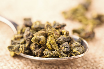 Fototapeta na wymiar Dry leaves of green tea and teaspoon