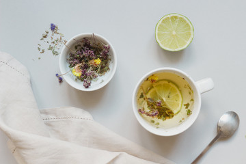Tea time. Cup of hot herbal tea and dry tea on the gray background, top view