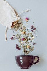 Tea time. Dry herbal tea and cup on the gray background, top view