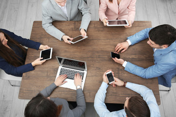 People sitting at table and using digital devices, top view