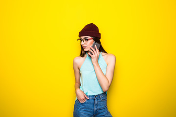 Portrait of a smiling woman talking on the phone over yellow background