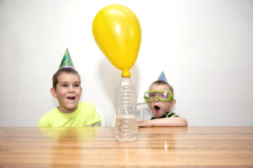 Two boys watching a chemistry experiment. children are surprised. Chemical reaction. the balloon is...