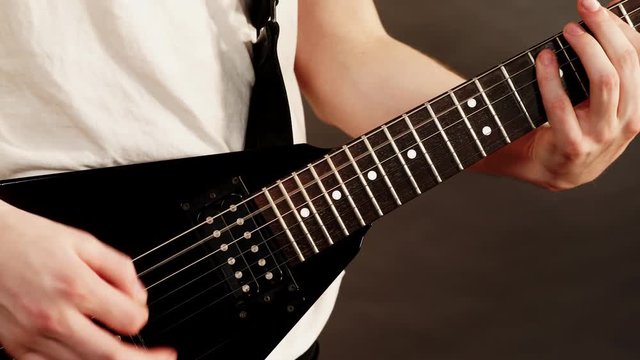 Male hands with electric guitar. Close up, part body adult person is holding instrument and playing. Hobby, music concept. 4K ProRes HQ codec