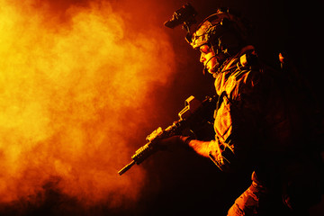 Security forces operator in Combat Uniforms with rifle, in the face of danger. Facing enemy, he is...