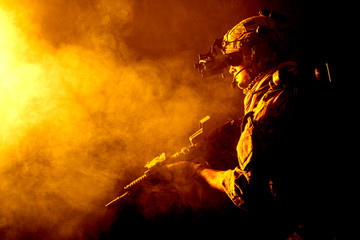 Security forces operator in Combat Uniforms with rifle, in the face of danger. Facing enemy, he is ready to fight. Studio contour silhouette shot, toned and colorized, backlight, profile side view