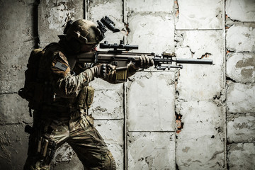 Army Ranger moving along the concrete wall on mission