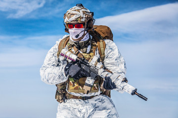 Army serviceman in winter camo somewhere in the Arctic. He wears chest rig and huge backpack,...
