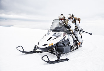 Army soldier in winter camo somewhere in the Arctic moving across the snow field riding tracked...