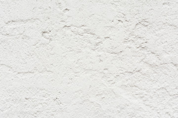 The texture of the old wall is white, there are fractures of the white protective layer of plaster from the effects of high humidity and atmospheric phenomena
