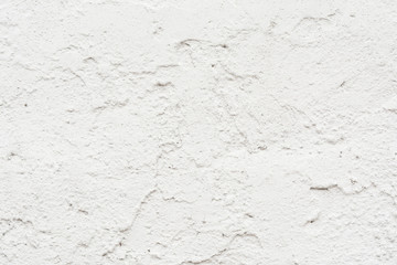 The texture of the old wall is white, there are fractures of the white protective layer of plaster from the effects of high humidity and atmospheric phenomena