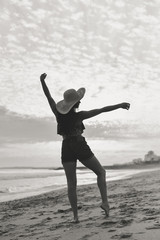 Obraz premium Black and white beach silhouette of the woman dancing during beautiful sun dawn. Natural light darkness background outdoors