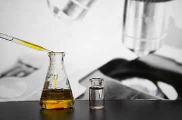 drop of yellow solution in to science flask with microscope