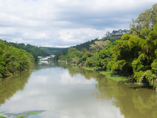 Panoramica of tranquil river current and banks with forests in day of clouds
