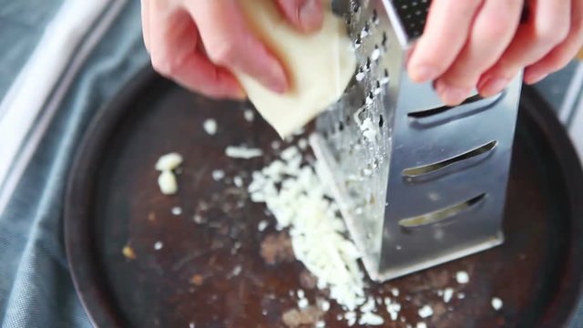 Using a grating tool to manually grate cheese