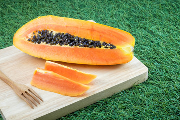 Fresh papaya sliced on wooden board and grass background.
