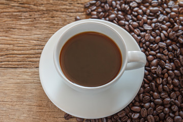 Coffee cup and coffee beans on old wood background