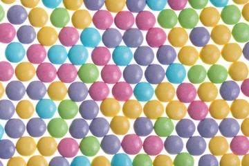Round pastel candies in a pattern on a white background
