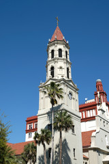 Fototapeta na wymiar Bell tower and front entrance to the Cathedral Basilica of St. Augustine in St Augustine, Florida. Blue skies and palm trees. Spanish Mission and Neoclassical architecture. No clouds.