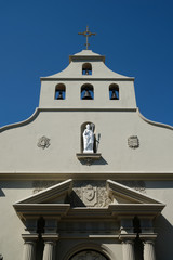 Facade of Cathedral Basilica of St. Augustine in St Augustine, Florida. Broken pediment and doric columns, mix of Neoclassical and Spanish Mission architecture. Bell tower, statue of St Augustine.