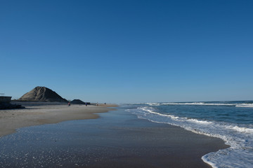 St Augustine Beach, Florida, on a cloudless later afternoon.  Sandy beach, calm waters, few people walking along the shore looking for seashells and relaxing. Florida beach holiday.