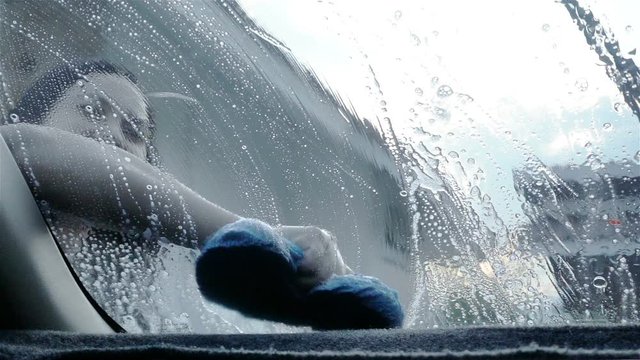 Slow motion, close up woman's hand cleaning car with blue sponge