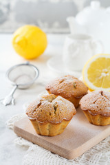 Lemon muffins with poppy seeds on a wooden stand on a light background. Selective focus.