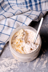 Healthy breakfast overnight oats with cocos and banana in a glass jar