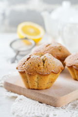Lemon muffins with poppy seeds on a wooden stand on a light background. Selective focus.