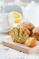 Lemon muffins with poppy seeds on a wooden stand on a light background. Selective focus.