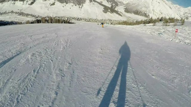 Fast ski ride behind snowboarder on winter day, POV