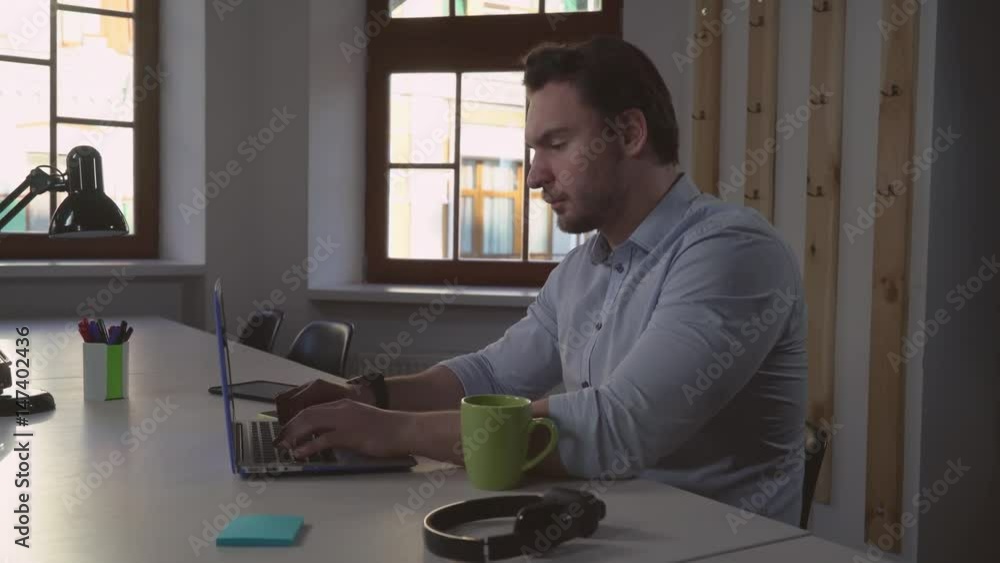 Poster Portrait middle aged man using computer. Handsome casual manager typing on laptop keyboard focused on screen. Manager ponders his new project. Designer sitting alone in room chatting online with