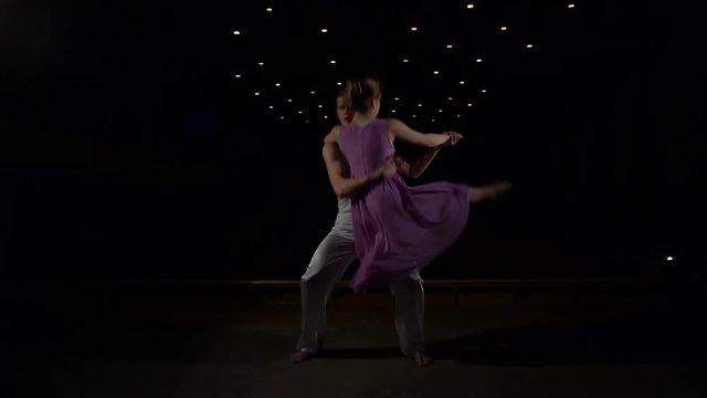 Young couple performing a contemporary dance pose on a stage, slow motion.