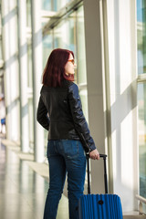 Passenger traveler woman in airport waiting for air travel.Smiling young woman admiring the airport view waiting for a flight.