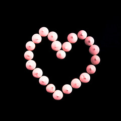 Small cookies laid in the shape of heart on black background. Toned