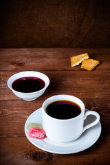 Cup of tea with jam, biscuits and marmalade on old wooden table against the background of burlap....