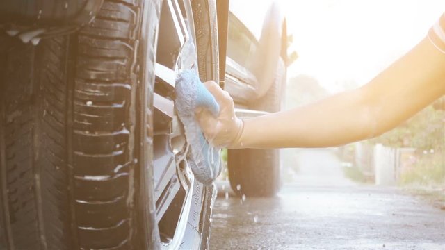 Slow motion, close up woman's hand cleaning car with blue sponge