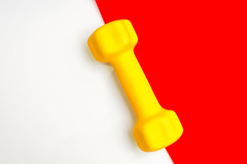 Yellow dumbbell for fitness on red and white background