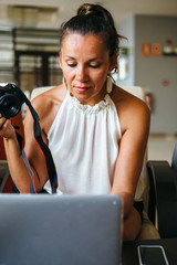 Woman working with laptop and photo camera