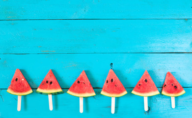 the summer watermelon slice popsicles on a blue rustic wood background. copy space for designer