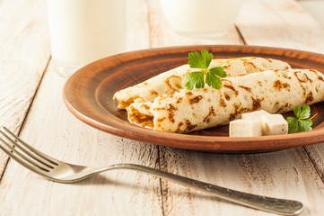 Food photography. Thin pancakes with filling and slices of cheese with herbs