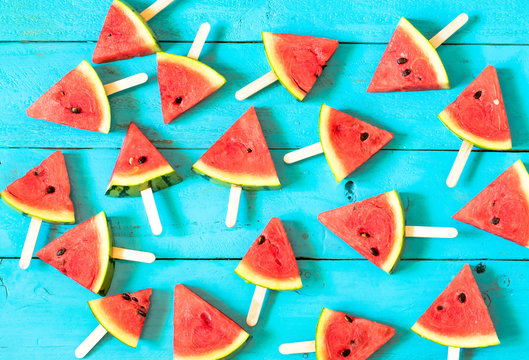 the summer watermelon slice popsicles on a blue rustic wood background