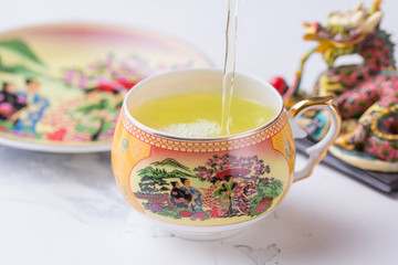 A cup of green tea on a white background. Hot drink pours into a cup with a pattern.